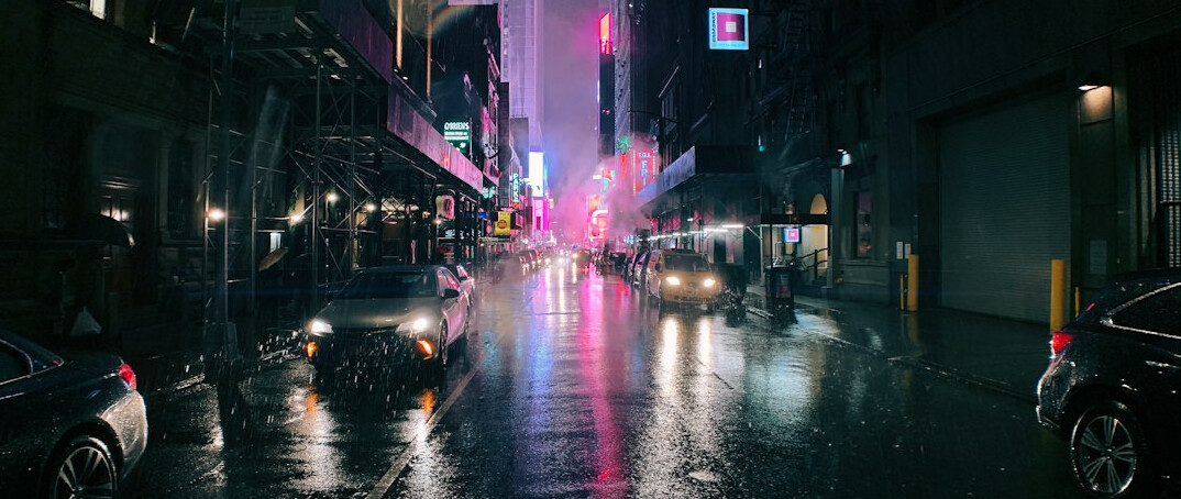 City street at night with glowing lights and wet pavement